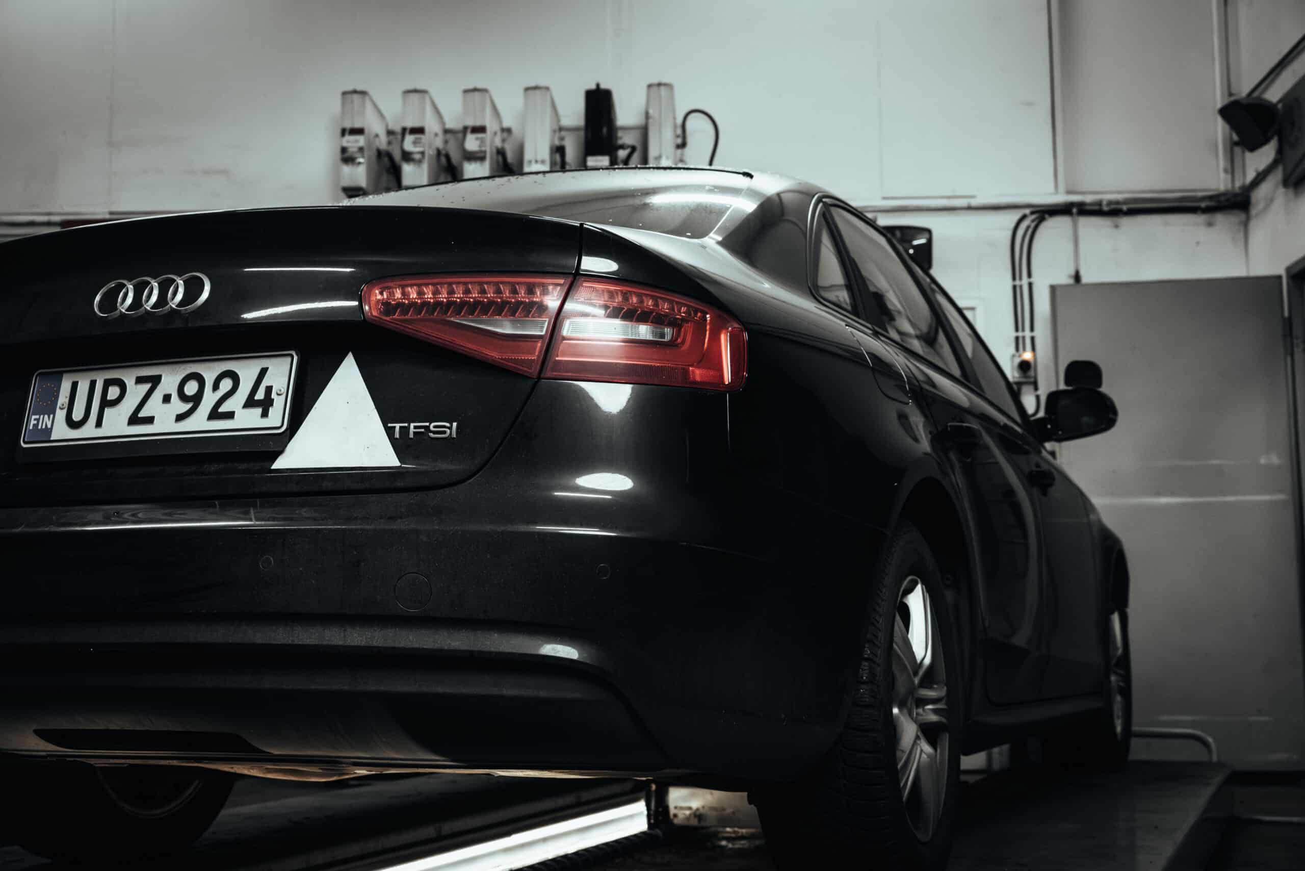 MaxSpeed Service – Autokorjaamo Raisio. Auto korjaamon hallissa takaapäin kuvattuna. Autossa opetuskolmio.